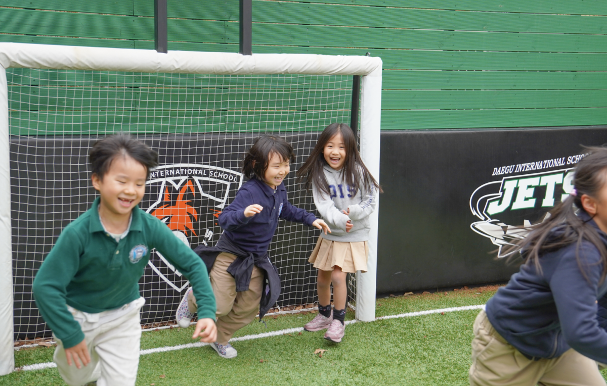 Elementary kids scurry across the field, avoiding to get caught by the tagger in a game of Red Light/Green Light. 
